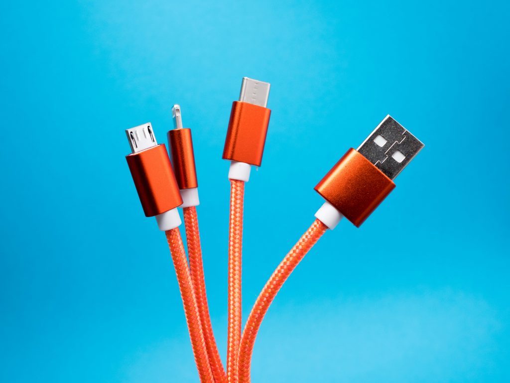 Various types of USB charging cables with orange cords against a blue background