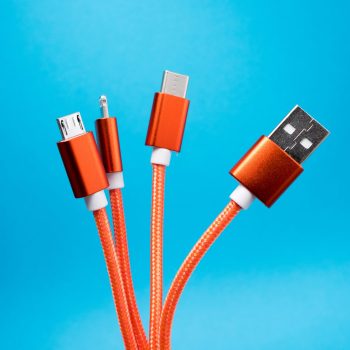 Various types of USB charging cables with orange cords against a blue background