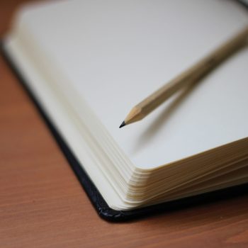 An open notebook with a pencil sitting on top