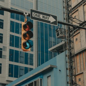 A street light with a green light and a "one way" sign pointing to the right