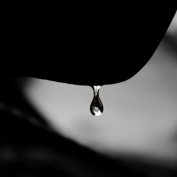 Close-up of a water droplet dripping from an unidentifiable surface