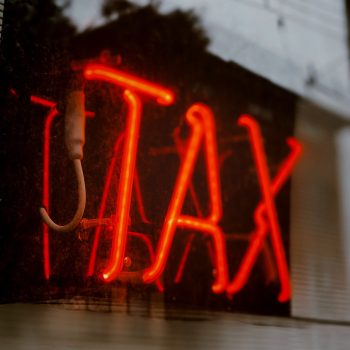 A red neon sign reading "Tax"