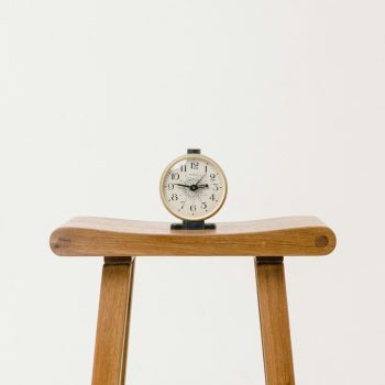 A clock sitting atop a wooden stool