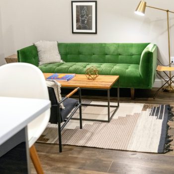 A living room with a green couch and various other decorations and furniture around it